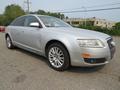 A 2006 Audi A6 in silver with a sleek design featuring prominent headlights and alloy wheels parked on a flat surface