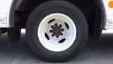 White wheel of a 2011 Ford Econoline with a dark tire and multiple lug nuts visible in the center