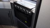 A black oven with four control knobs and a sleek design installed in a kitchen area of a 2022 Aspen Trail camper