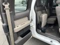 Interior view of a 2010 Ford F-150 passenger door with gray fabric seats and a tan door panel showing the window controls and door handle