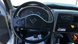 The interior of a 2019 International 4300 featuring a black steering wheel with gauges and controls, a gear shift, and a driver mat with the word thank