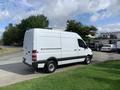 A 2017 Mercedes-Benz Sprinter van in white parked on a grassy area with a side view showing its sleek exterior and cargo space design