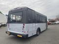 A 2017 Chevrolet Express bus with a gray rear, large windows, and red taillights parked in an industrial area