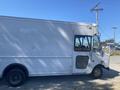 A white 2008 Ford Econoline cargo van with a boxy shape and large windows parked on a gravel surface