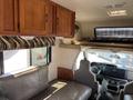 Interior of a 2012 Ford Econoline featuring a couch and overhead cabinets with patterned fabric above the windows