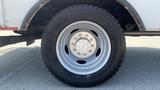 A close-up view of a silver wheel with a multi-lug pattern mounted on a large black tire labeled Goodyear on a 2011 Ford F-450 SD