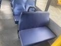 A blue upholstered seat with a foldable backrest typical of a public transportation vehicle interior