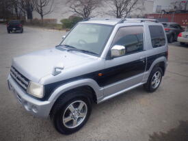 A silver and black 2007 Mitsubishi Pajero Mini parked with a distinctive design featuring chrome wheels and a scoop on the hood