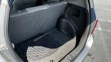 Interior view of the cargo space in a 2006 Honda Fit showing gray upholstery and a rubber floor mat