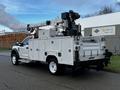 A white 2018 Ford F-550 utility truck equipped with a boom lift and various storage compartments on the sides