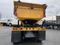 A 2016 International 7400 truck with a yellow dump bed and visible tail lights showcasing a rear view of the vehicle