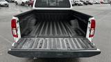 Open bed of a white 2016 Nissan Frontier pickup truck showing a textured black liner and metal surface