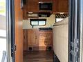 Interior of a 2012 Ford Econoline featuring wood cabinetry a microwave a countertop with a stove and a sofa area