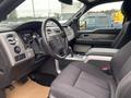 Interior view of a 2014 Ford F-150 showing the dashboard steering wheel and seats in a dark color scheme