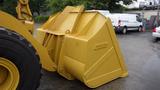 A large yellow bucket attachment designed for a Caterpillar 972M XE wheel loader with a robust and angular shape