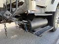 A close-up view of a black cylindrical tank attached to a 2009 International 7500 truck with visible hoses and metal connections near the vehicle's undercarriage