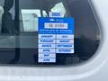 A blue and white sticker displaying a certificate of approval with months listed and a certificate number on a vehicle window