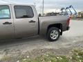 2013 Chevrolet Silverado Hybrid with a silver exterior and off-road tires parked on the side of the road