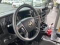 Interior view of a 2018 Chevrolet Express with a black steering wheel and dashboard featuring gauges and controls along with cup holders