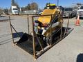 A yellow 2024 AGT KTT23 Mini Skid Steer with a front bucket attachment and track wheels positioned in a metal frame enclosure