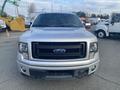 A silver 2014 Ford F-150 with a black grille and large headlights facing forward