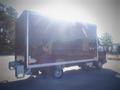 A 2013 Mitsubishi Fuso FE 160 box truck with a dark exterior and a large cargo area is parked with sunlight reflecting off its surface