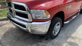 A red 2013 RAM 2500 pickup truck with chrome accents and black tires parked in a driveway