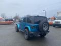 A blue 2020 Jeep Wrangler with a black hardtop and oversized tires parked in a lot