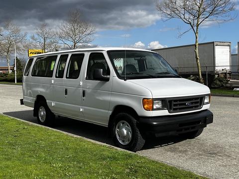 A white 2004 Ford Econoline van is parked, featuring a boxy design, four side doors, and medium-sized wheels