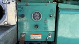 A green control panel featuring a gauge labeled Amperes a start and stop switch an emergency relay indicator and a warning label