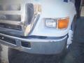 A white 2006 Ford F-650 with a prominent chrome grille and headlight visible in the foreground featuring minor scratches on the bumper