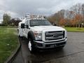 A 2016 Ford F-550 truck with a white exterior features a flatbed and orange safety lights on top