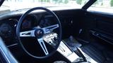 Interior view of a 1971 Chevrolet Corvette Stingray with a black dashboard and leather seats featuring a classic steering wheel and instrument panel