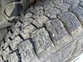 Close-up of a worn tire with deep tread patterns showing signs of use on a vehicle