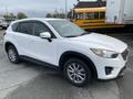 A white 2016 Mazda CX-5 SUV is parked with a side view showing its sleek design and alloy wheels