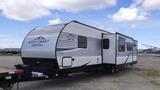 A 2021 Forest River 312BH East To West Della Terra travel trailer with a sleek aluminum exterior featuring a black and silver design and large windows