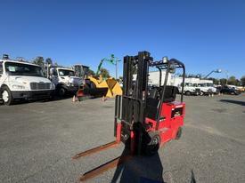 A red 2013 Raymond forklift with two long forks in the front parked in a lot surrounded by various vehicles