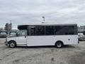 A 2017 Chevrolet Express bus with a white body and large windows is parked, featuring a high roof and side entry door