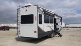 A 2021 Forest River Cedar Creek recreational vehicle with a sleek design featuring multiple windows and an extending awning on the passenger side