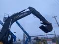 A 2014 John Deere 350G excavator with a large bucket attachment extended upward against a cloudy sky