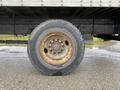 Close-up of a large, worn tire mounted on a truck wheel showcasing dirt and rust on the rim