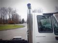 A 2006 International 4300 truck with a large chrome exhaust stack visible in the foreground