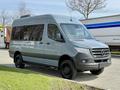 A gray 2019 Mercedes-Benz Sprinter van with a sleek design and large side windows parked on a roadway