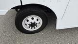 Close-up of a tire and wheel of a 2006 Ford Econoline showing a white rim with multiple lug nuts and a black tire