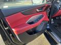 The interior door panel of a 2023 Acura MDX featuring a red leather and dark wood trim design with control buttons and a handle