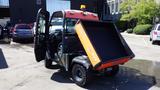 A 2013 Kubota RTV 1100 utility vehicle with an orange and black dump bed and an open driver's door