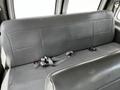 A black leather bench seat from a 2004 Ford Econoline with two seatbelt buckles and a single seatbelt lying across the seat