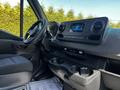 Interior view of a 2022 Mercedes-Benz Sprinter featuring a sleek dashboard with a touchscreen display and climate controls along with a steering wheel and cup holders