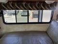 Interior view of a 2012 Ford Econoline showing a tan leather seat with a window covered by a patterned curtain