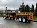 A 2015 International 3000 MT6 with yellow and black colors attached to a trailer carrying palm trees